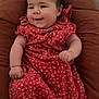 arm, baby, child, comfort, cozy, cushion, cute, face, floral_pattern, hand, happy, head, indoor, infant, person, red_dress, seated, skin, smile, soft_lighting