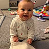 baby, infant, smiling, white_clothing, heart_pattern, carpet, toys, blanket, playmat, cute, child, indoors, happy, sitting, face, person, soft_lighting, floor, crawling, room