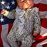 baby, infant, american_flag, floral_onesie, sunlight, portrait, cute, child, newborn, soft_light, patterned_clothing, stars, stripes, red, white, blue, lying_down, peaceful, small_hands, adorable