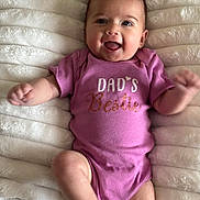 Aria is registered to the contest to win money with this photo: baby, infant, smiling, pink_onesie, clothing, happy, face, arms, legs, blanket, texture, lying_down, cute, child, person, soft, cozy, expression, joyful, indoors