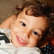 Braylon joined the competition — help win amazing prizes! toddler, child, smiling, curly_hair, white_shirt, nike_logo, indoors, carpet, happy, portrait, face, cute, young_child, close_up, person, casual_clothing, bright_eyes, skin, head, background_blur