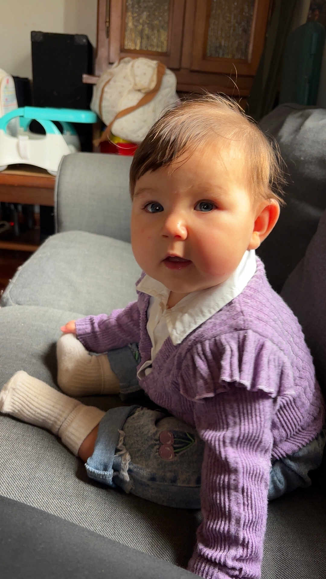 Loëlya participe au concours pour gagner de l'argent avec cette photo : baby, child, indoor, couch, purple_sweater, white_socks, curly_hair, face, blue_eyes, sitting, cozy, furniture, portrait, casual_clothing, cute, chubby_cheeks, home, soft_lighting, denim_pants, curious