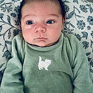 Eren participe au concours pour gagner de l'argent avec cette photo : baby, infant, newborn, onesie, green_clothing, embroidered_cat, blanket, pillow, floral_pattern, face, eyes, hair, hands, portrait, indoors, closeup, skin, cute, sleepy, bedding