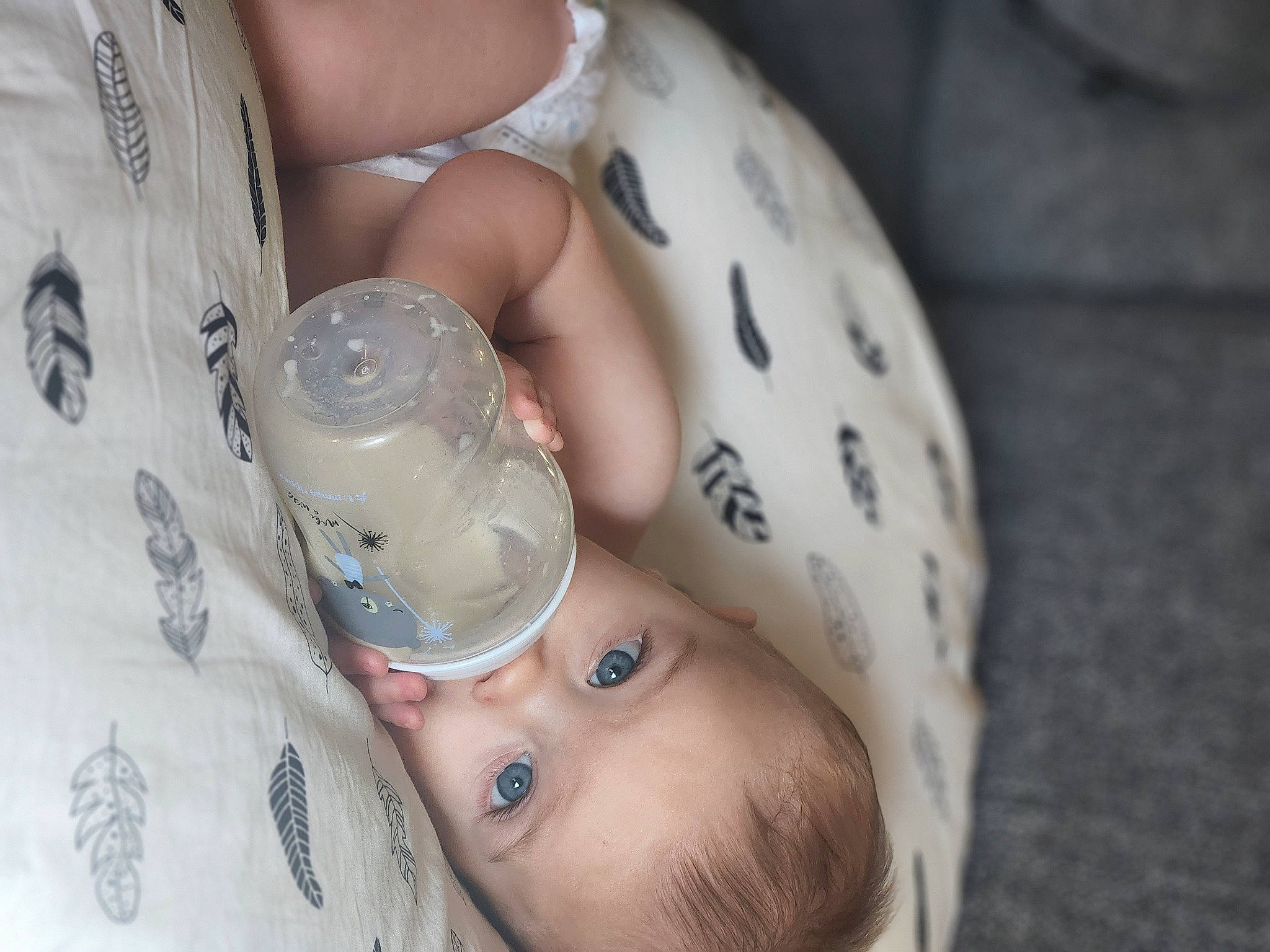 Cillian is registered to the contest to win money with this photo: baby, baby_products, bottle, cheek, drinking, drinkware, ear, eyebrow, eyelash, finger, fluid, hand, health_care, human_leg, mouth, nail, person, personal_protective_equipment, plastic_bottle, skin