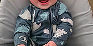 Leo joined the competition — help win amazing prizes! baby, infant, smiling, onesie, dinosaur_pattern, cushion, soft_fabric, happy, child, portrait, sitting, cute, indoor, young_child, comfortable, cozy, small_hands, feet, face, expression
