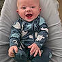 baby, infant, smiling, onesie, dinosaur_pattern, cushion, soft_fabric, happy, child, portrait, sitting, cute, indoor, young_child, comfortable, cozy, small_hands, feet, face, expression