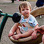 balance, barefoot, casual_clothing, child, curious, cute, daylight, fun, holding_hand, outdoor, overalls, park, person, play, playground, seat, short_hair, spinner, toddler, toy
