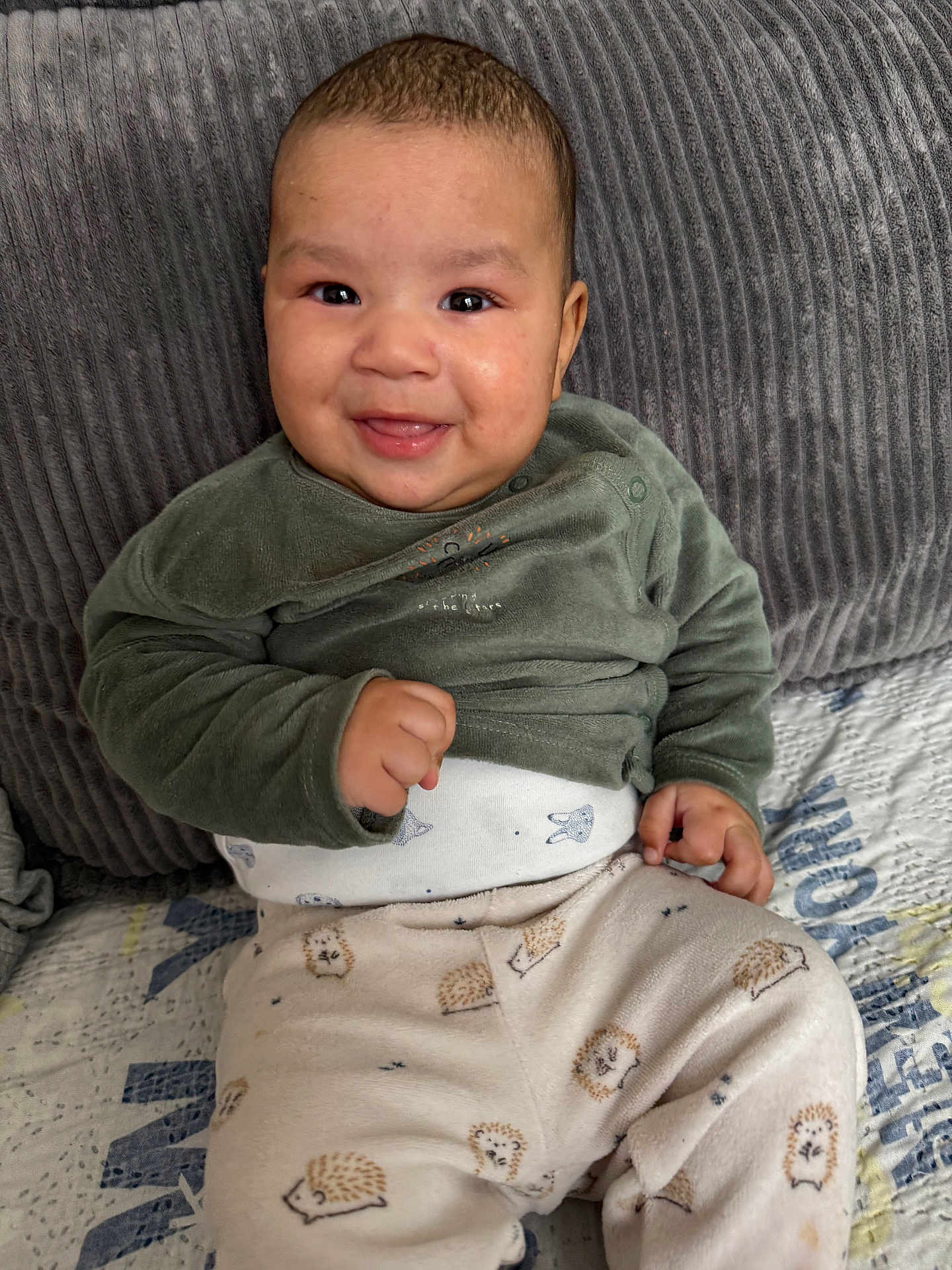 Maëlan participe au concours pour gagner de l'argent avec cette photo : baby, smiling, child, infant, clothing, green_shirt, patterned_pants, hedgehog_pattern, couch, pillow, gray_pillow, happy, indoor, portrait, sitting, cute, face, young_child, cozy, home