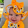 baby, child, sunflower, hat, bow, yellow_clothing, smiling, happy, outdoor, cushion, face, portrait, infant, sitting, nature, bright_colors, cute, young_child, headwear, joyful
