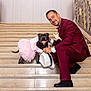 Sika is registered to the contest to win money with this photo: accessory, animal, celebration, crouching, dog, dress, fashion, formal, friendship, happy, hat, indoor, man, marble, pet, pink, portrait, smile, stairs, suit