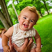 Duke is registered to the contest to win money with this photo: baby, casual_clothing, child, face, family, grass, greenery, hand, happy, holding, nature, outdoor, person, playful, portrait, smiling, summer, sunlight, toddler, trees