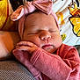 baby, newborn, sleeping, pink_bow, headband, pink_outfit, infant, cushion, blanket, closeup, portrait, cozy, peaceful, child, human, skin, hand, face, resting, indoors