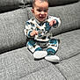 baby, child, clothing, couch, cozy, cute, face, gray_couch, happy, home, indoor, infant, pants, person, portrait, shoes, sitting, smiling, sweater, young_child