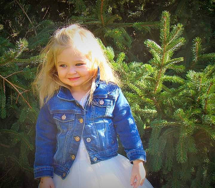 Taylynn is registered to the contest to win money with this photo: beauty, branch, clothing, denim, eye, face, facial_expression, fawn, forest, grass, happy, iris, joy, long_hair, people_in_nature, person, plant, sleeve, smile, toddler