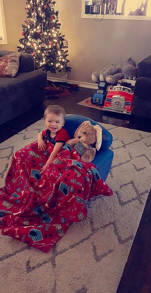 Eric is registered to the contest to win money with this photo: baby, beauty, child, christmas_tree, cloud, couch, event, floor, flooring, fun, happy, holiday, human_body, joy, lap, living_room, person, red, sky, toddler