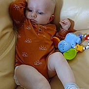 Lyzio participe au concours pour gagner de l'argent avec cette photo : baby, child, couch, toy, elephant_toy, orange_onesie, socks, indoor, furniture, leather, infant, cute, relaxed, seated, person, small_toy, patterned_clothing, looking_away, light_skin, casual