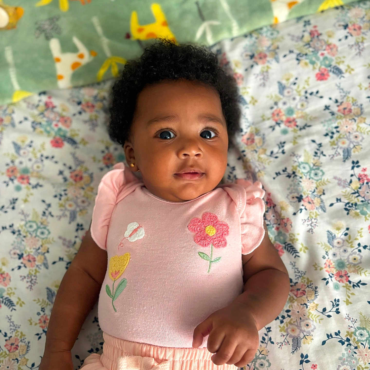 Daniya joined the competition — help win amazing prizes! baby, child, infant, curly_hair, pink_clothing, flower_embroidery, blanket, floral_pattern, animal_pattern, lying_down, cute, portrait, indoors, soft_lighting, adorable, young_child, skin_tone, hand, face, expression
