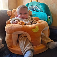 Gabriel a rejoint le concours — aidez-le/la à gagner de superbes lots ! baby, infant, smile, plush_seat, stuffed_toy, bib, socks, pants, sofa, cushion, living_room, portrait, cute, chubby_cheeks, toy, seat, cozy, window_light, happy, child