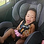 toddler, child, car_seat, car_interior, smiling, happy, toy, seatbelt, clothing, window, sunlight, headrest, safety, baby, seat, person, vehicle, fun, cute, playful
