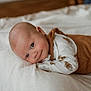 Waylon is registered to the contest to win money with this photo: baby, infant, newborn, child, smiling, face, eyes, lying_down, bed, blanket, pillow, onesie, animal_print, brown_clothing, cozy, portrait, bedroom, skin, head, cute