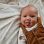 Waylon is registered to the contest to win money with this photo: baby, infant, child, face, tongue, sticking_out_tongue, smile, overalls, onesie, clothing, blanket, bedding, fabric, cheeks, eyes, portrait, lying_down, cute, happy, candid