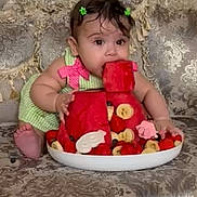 Nazli joined the competition — help win amazing prizes! baby, child, watermelon, fruit, strawberries, banana, green_dress, hair_clips, couch, patterned_furniture, curious, cute, food, snack, indoor, portrait, sitting, colorful, playful, summer