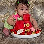 Nazli is registered to the contest to win money with this photo: baby, child, watermelon, fruit, banana, strawberry, plate, green_dress, hair_clips, couch, ornate_furniture, curious, indoor, food, snack, cute, sitting, person, fruit_slices, decorative