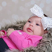 Nasai is registered to the contest to win money with this photo: adorable, baby, child, cute, eyes, face, fashion_accessory, fur_blanket, hands, headband, indoor, infant, laying_down, newborn, peaceful, pink_clothing, portrait, skin, soft_texture, white_bow
