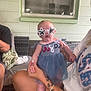 Layla joined the competition — help win amazing prizes! baby, child, sunglasses, star_shaped_glasses, blue_dress, tattoo, person, hand, arm, porch, window, light_fixture, seated, indoor, furniture, cushion, expression, cute, holding, skin
