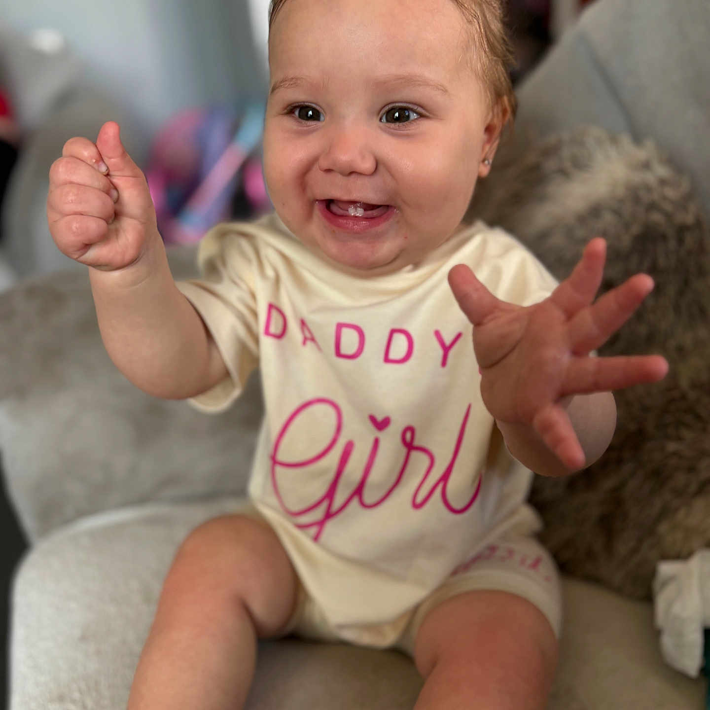 Lshae is registered to the contest to win money with this photo: baby, child, cozy, cute, expression, eyes, face, furniture, girl, hand, happy, indoor, infant, pillow, portrait, shirt, sitting, skin, smiling, text_on_clothing