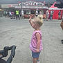 Miley is registered to the contest to win money with this photo: toddler, child, blonde, pink_top, blue_shorts, sneakers, waving, stroller, outdoor, side_view, people, crowd, pizza_stand, signage, concrete, daylight, casual_clothing, event, street, hat