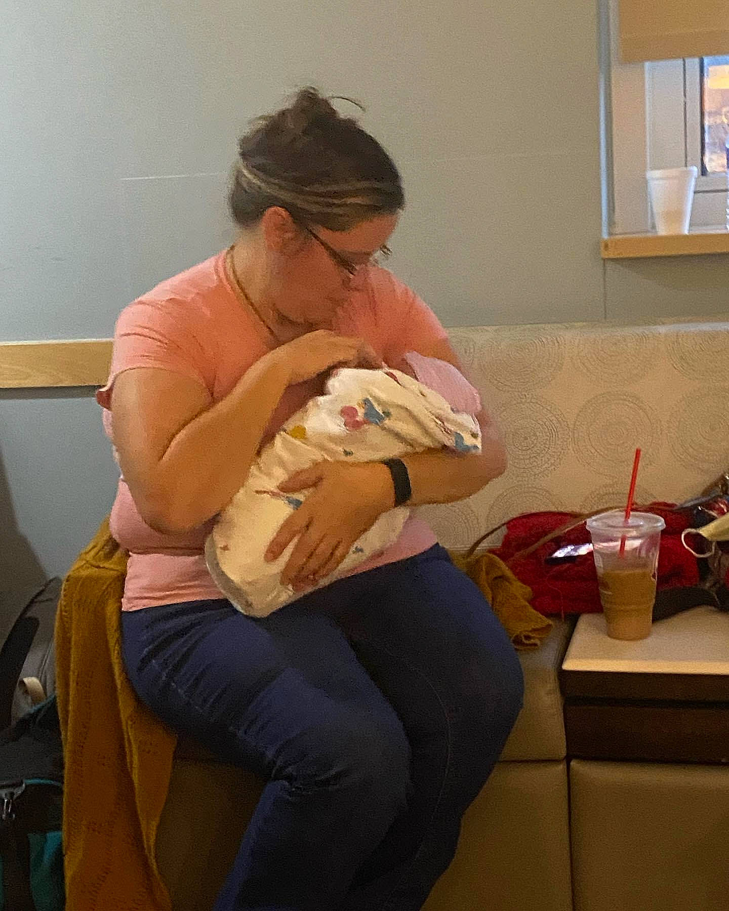 Melanie is registered to the contest to win money with this photo: abdomen, baby, backpack, comfort, conversation, elbow, eyewear, glasses, human_leg, joint, knee, lap, person, room, shoulder, sitting, t_shirt, table, thigh, trunk