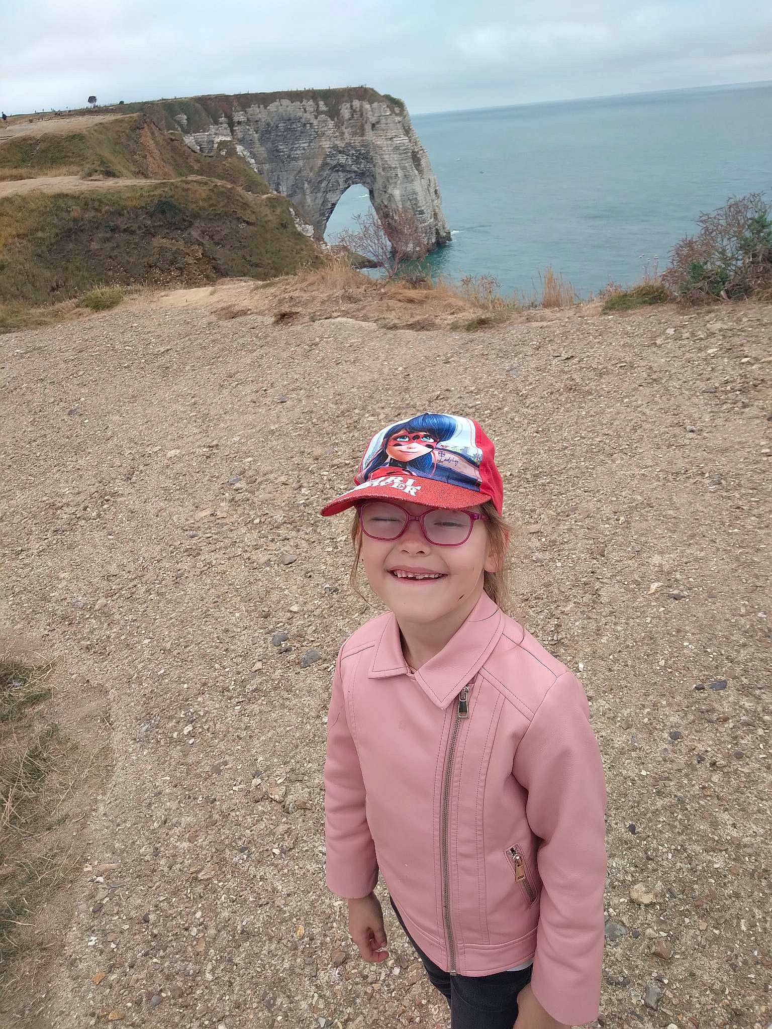 Shanna participe au concours pour gagner de l'argent avec cette photo : baseball_cap, cap, ecoregion, eyewear, fashion_accessory, grass, grassland, happy, hat, headwear, hill, joy, landscape, person, recreation, rock, sky, smile, soil, sun_hat