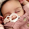 baby, pacifier, sleeping, infant, pink_clothing, corduroy, face, hand, closed_eyes, soft_background, portrait, child, cute, resting, newborn, baby_garment, peaceful, indoors, blanket, comfort