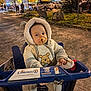baby, child, pacifier, shopping_cart, coat, hood, bear_ears, night, outdoor, autumn, tree, leaves, car, parking_lot, person, cute, warm_clothing, infant, face, urban