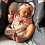 baby, infant, sleeping, pink_headband, pink_cardigan, floral_dress, baby_seat, cushion, feet, hand, peaceful, indoors, child, cute, adorable, newborn, resting, soft_lighting, portrait, cozy
