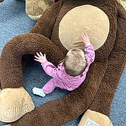 Elowyn is registered to the contest to win money with this photo: toddler, child, plush_toy, giant_teddy_bear, pink_clothing, carpet, soft_toy, baby, indoors, crawling, cute, floor, stuffed_animal, child_playing, brown, beige, young_child, playtime, toy, infant