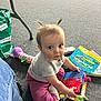 Elowyn is registered to the contest to win money with this photo: toddler, child, baby, sitting, carpet, books, toy, indoor, clothing, socks, hair, face, eyes, expression, floor, person, reading, colorful, playtime, curious