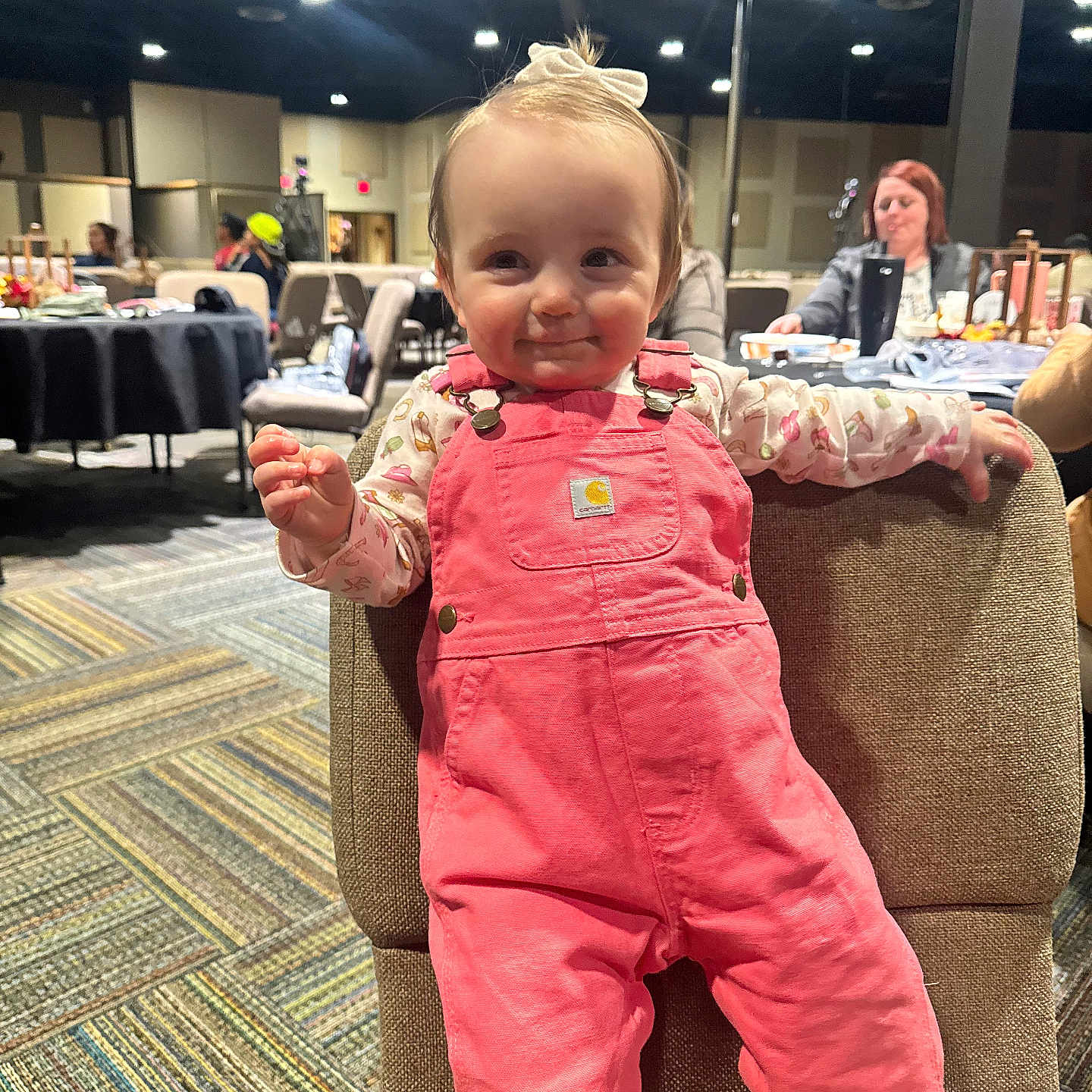 Elowyn joined the competition — help win amazing prizes! baby, background, carpet, chair, child, clothing, cute, face, happy, headband, indoor, lighting, people, person, pink_overalls, room, seated, smile, toddler, woman
