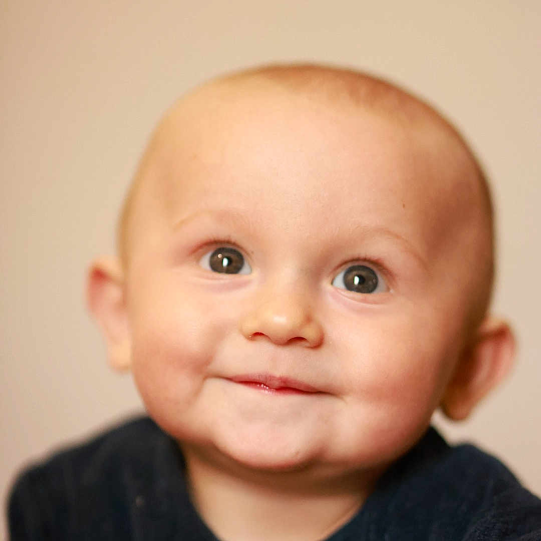 Tonyo participe au concours pour gagner de l'argent avec cette photo : baby, background, child, closeup, clothing, cute, expression, eyes, face, happy, head, indoor, infant, innocence, person, portrait, skin, smile, soft, young