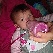 Roseley is registered to the contest to win money with this photo: baby, bottle, feeding, hand, pink, clothing, cute, infant, face, eyes, person, bed, blanket, sleepwear, child, resting, indoors, human, portrait, young