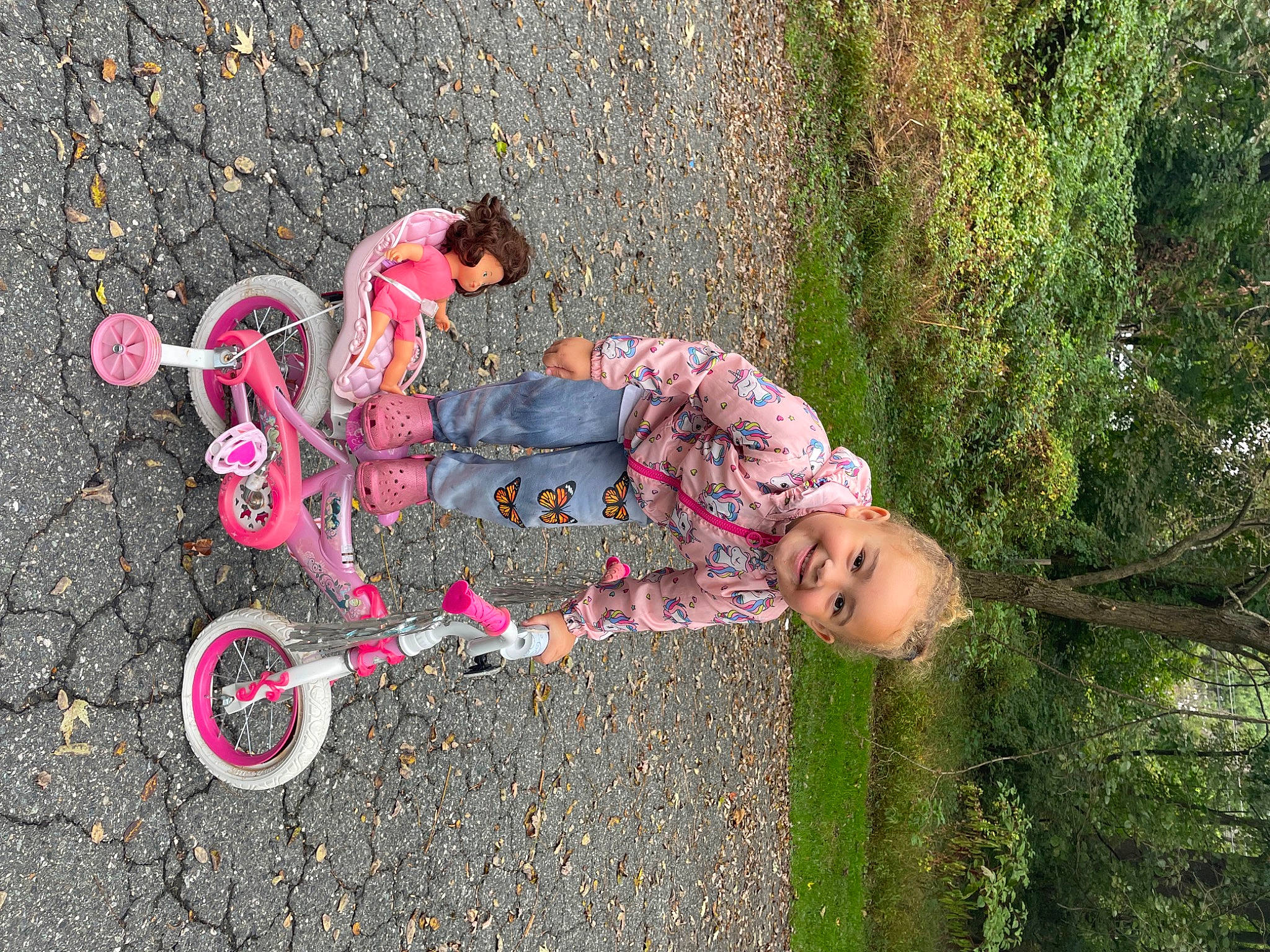 Helena is registered to the contest to win money with this photo: asphalt, bicycle_accessory, bicycle_handlebar, bicycle_tire, bicycle_wheel, child, grass, joy, leisure, magenta, people_in_nature, person, plant, recreation, riding_toy, road_surface, sidewalk, tire, toddler, tree