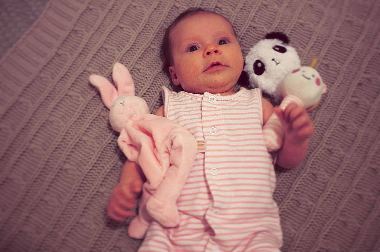 Maliah is registered to the contest to win money with this photo: arm, baby, cheek, child, eye, face, finger, gesture, hand, head, person, pink, skin, smile, stuffed_toy, teddy_bear, thumb, toddler