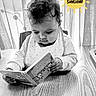 baby, child, book, reading, curly_hair, bib, high_chair, table, indoor, monochrome, black_and_white, cute, concentration, sun_graphic, text_overlay, wood, pattern, clothing, face, portrait