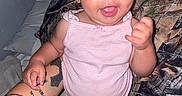 Journey is registered to the contest to win money with this photo: baby, child, infant, smiling, pink_onesie, tattooed_arm, hand, bed, pillow, camo_pattern, indoor, person, cute, joyful, skin, face, happy, standing, support, expression