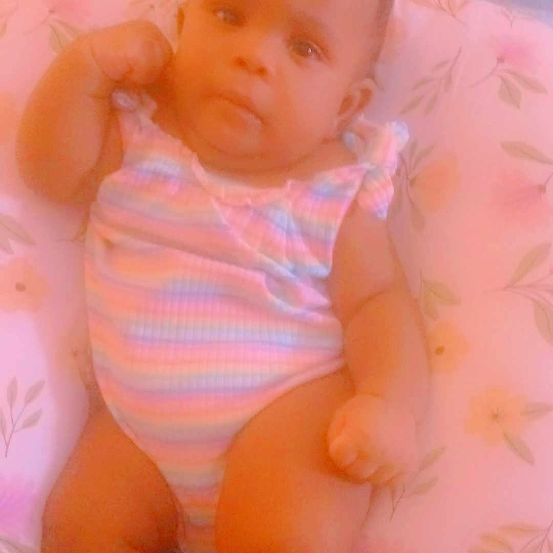 Shaylah is registered to the contest to win money with this photo: baby, infant, child, onesie, cushion, floral_pattern, socks, pink, pastel_colors, soft_focus, portrait, indoor, cute, chubby, relaxed, person, newborn, babywear, seated, comfortable