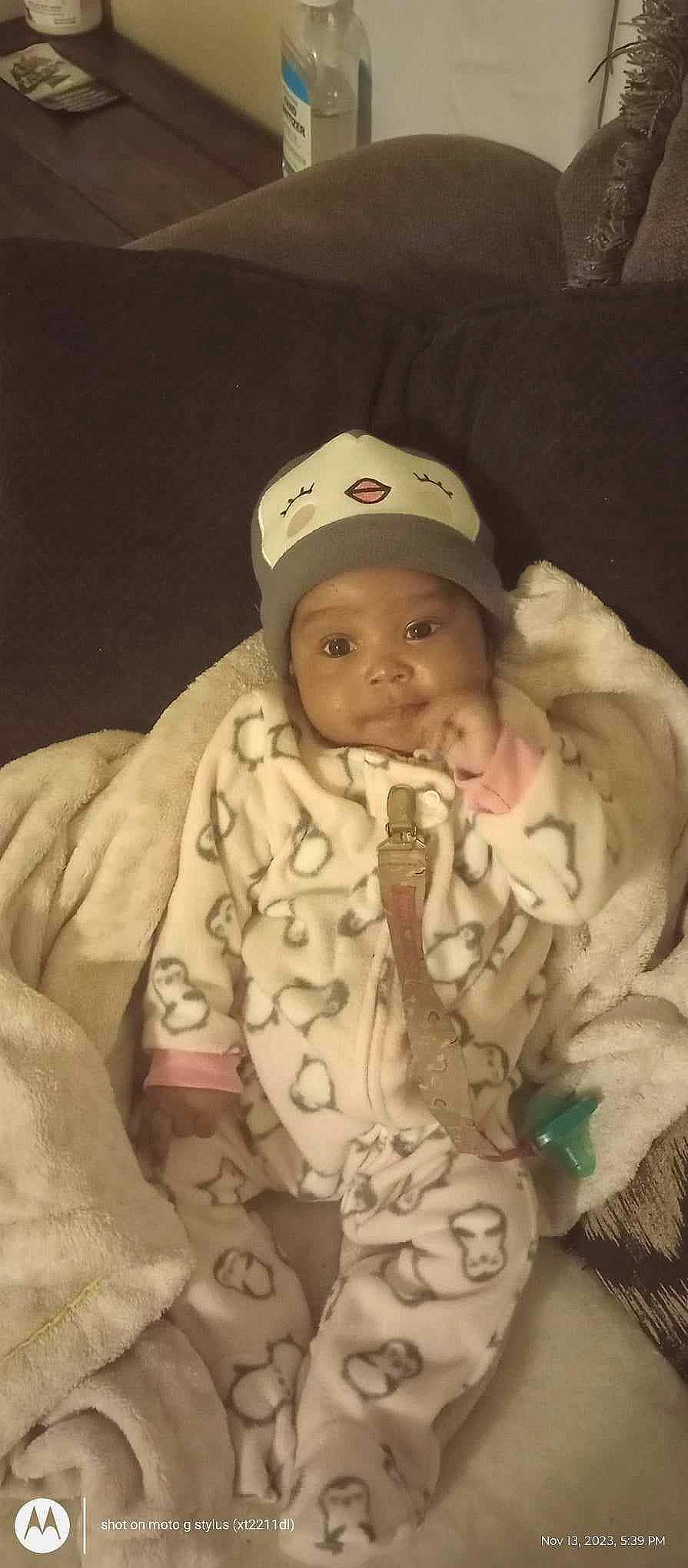 Nevaeh is registered to the contest to win money with this photo: baby, baby_products, baby_safety, baby_sleeping, baby_toddler_clothing, baseball_cap, cap, cheek, child, comfort, face, head, headgear, headwear, linens, outerwear, person, sitting, skin, sleeve