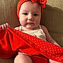 baby, child, infant, red_headband, polka_dots, red_clothing, sitting, couch, beige_background, cute, face, hand, legs, indoor, portrait, young_child, headwear, fabric, holding, expression