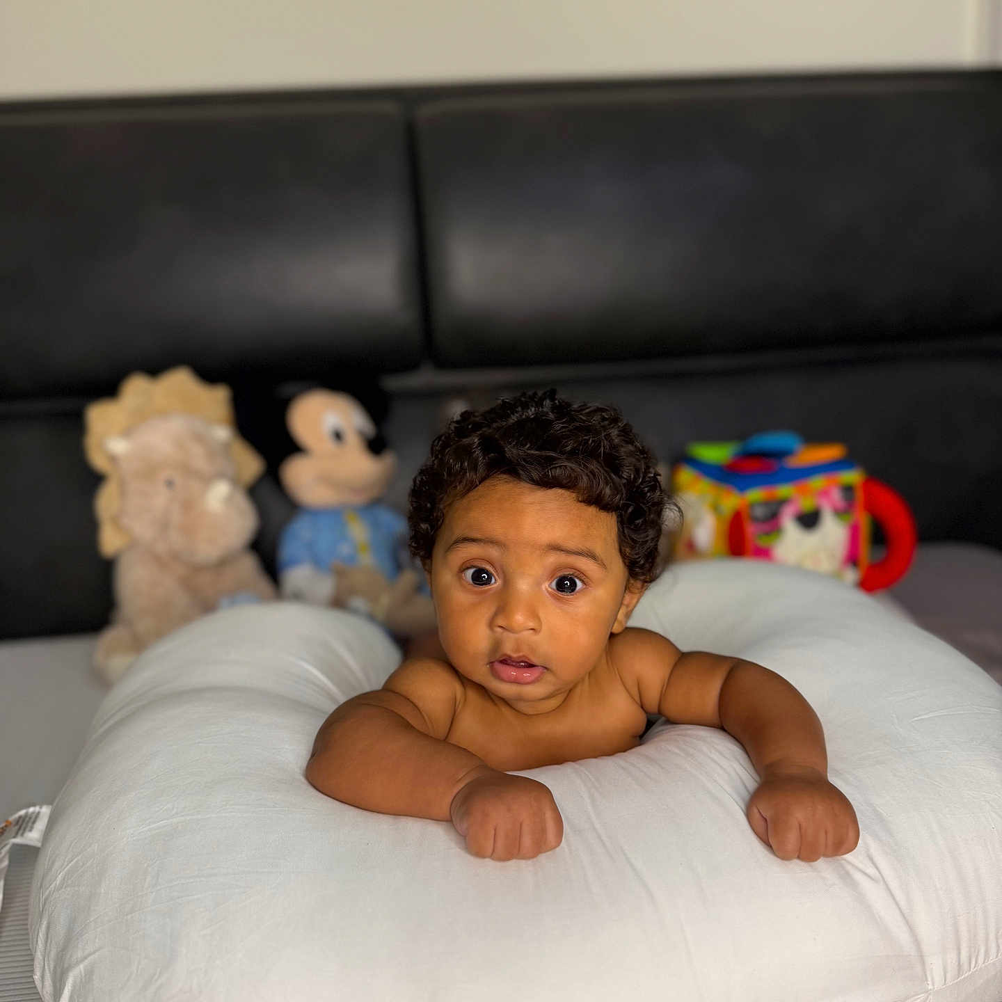 Damier is registered to the contest to win money with this photo: baby, bedroom, child, couch, curly_hair, cute, expression, furniture, indoor, infant, lion_toy, mickey_mouse, pillow, plush_toy, portrait, resting, skin, soft_toys, stuffed_animal, wide_eyes