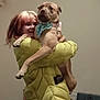 Sklar is registered to the contest to win money with this photo: person, dog, indoor, yellow_jacket, bandana, smiling, hugging, pet, canine, happy, casual, clothing, warm, domestic, friendship, animal, home, portrait, light, cozy